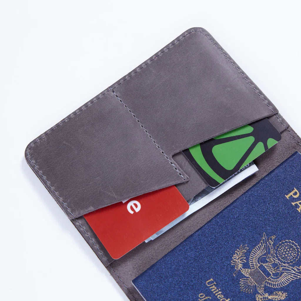 Hand holding gray leather passport cover with Great Seal of the United States highlighting compact size